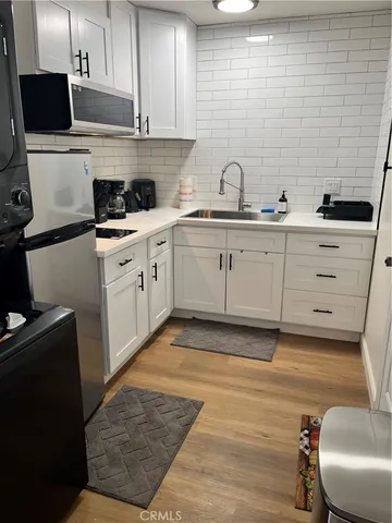 a kitchen with stainless steel appliances a sink a stove a microwave a refrigerator and cabinets