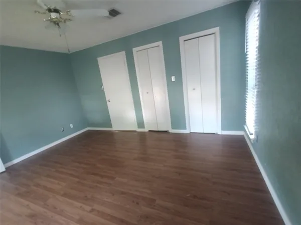 an empty room with wooden floor and windows