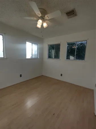 an empty room with windows and fan