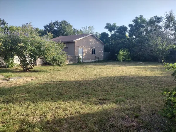 a view of a house with a yard and a large tree