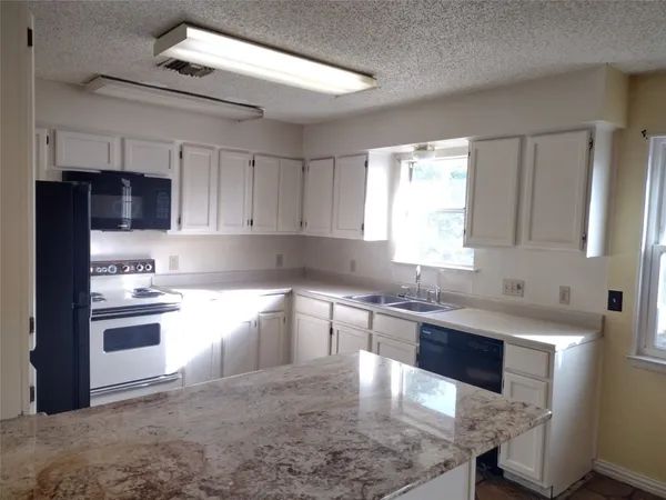 a kitchen with granite countertop a stove sink and cabinets