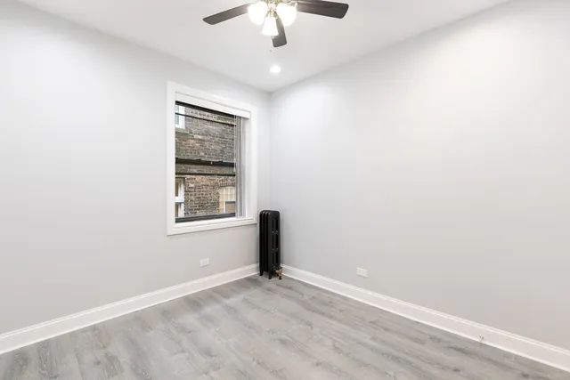 an empty room with a window and a fan
