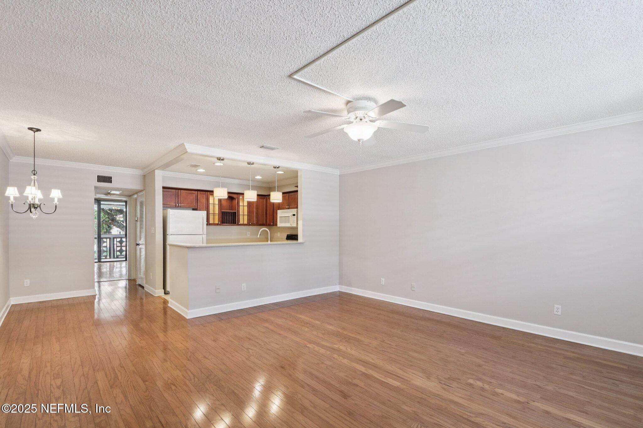 1810 Sevilla Boulevard West, Unit 307 Atlantic Beach, FL 32233 - Photo 2 of 28 an empty room with wooden floor and ceiling fan