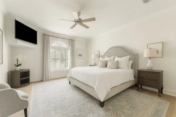 a spacious bedroom with a bed and a flat tv screen on dresser