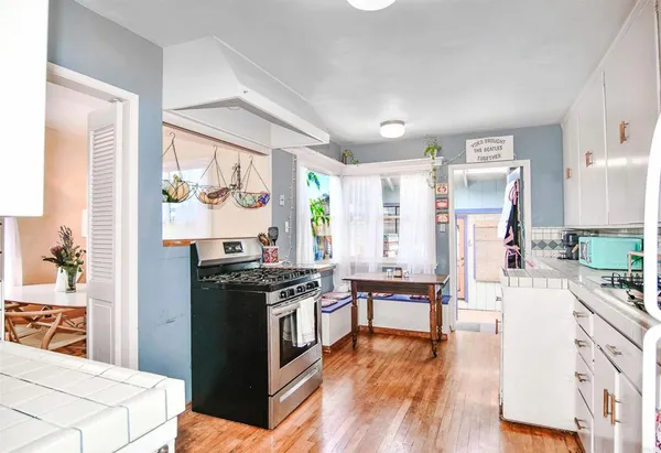 a kitchen with stainless steel appliances a stove a sink a refrigerator and wooden floor