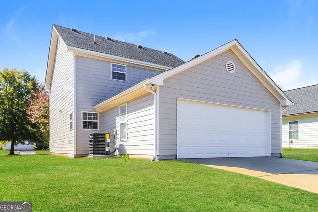 a front view of house with yard and trees in the background