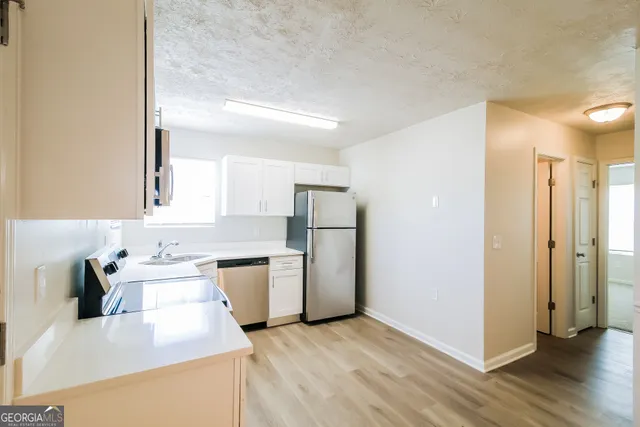a kitchen with a sink a refrigerator and wooden floor