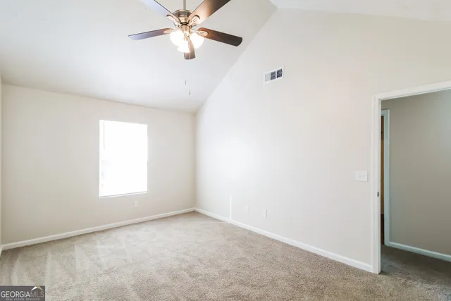 an empty room with windows and fan
