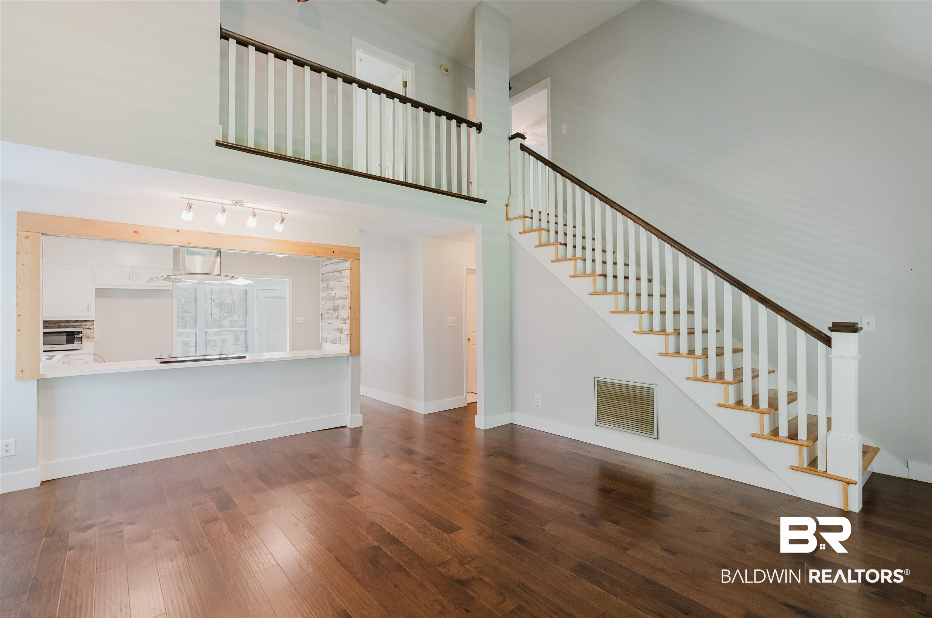 20460 Bishop Road Fairhope, AL 36532 - Photo 13 of 41 Unfurnished living room with wood finished floors, stairs, baseboards, and a high ceiling