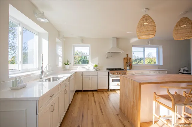 a large kitchen with kitchen island granite countertop a large window a sink and white appliances