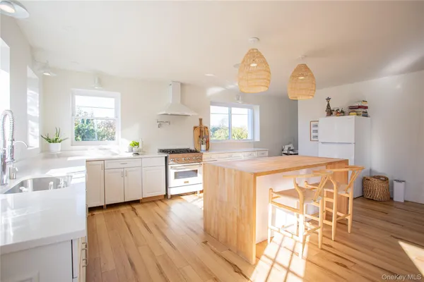 a large kitchen with kitchen island a island a sink a stove and wooden floor