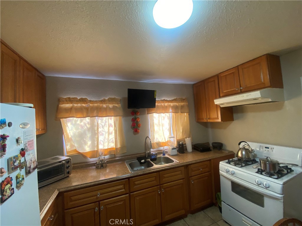 12065 Aztec Lane Adelanto, CA 92301 - Photo 43 of 64 a kitchen with stainless steel appliances a sink stove and window
