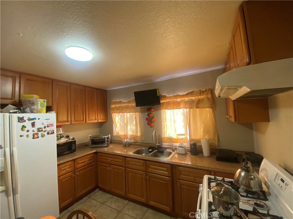12065 Aztec Lane Adelanto, CA 92301 - Photo 44 of 64 a kitchen with stainless steel appliances granite countertop a refrigerator a sink dishwasher a stove and white countertops with wooden floor