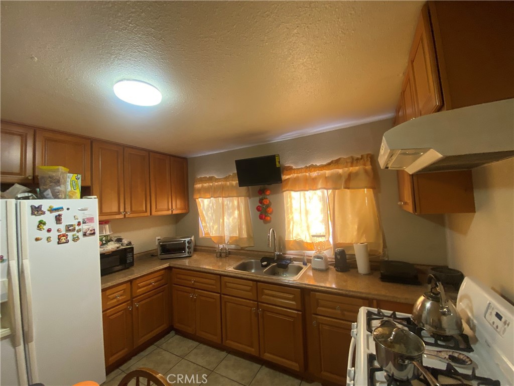 12065 Aztec Lane Adelanto, CA 92301 - Photo 45 of 64 a kitchen with stainless steel appliances a refrigerator a sink a stove a chimney a refrigerator and cabinets