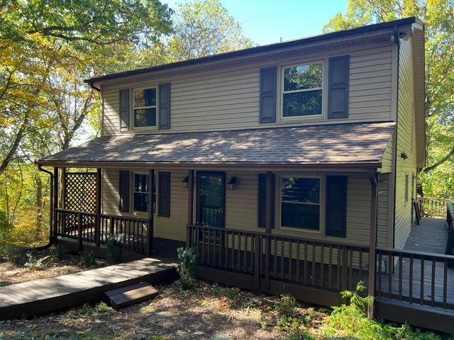 a view of house with wooden fence and a tree
