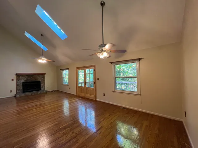 a view of an empty room with window and wooden floor