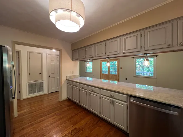 a kitchen with stainless steel appliances granite countertop a sink and cabinets with wooden floor