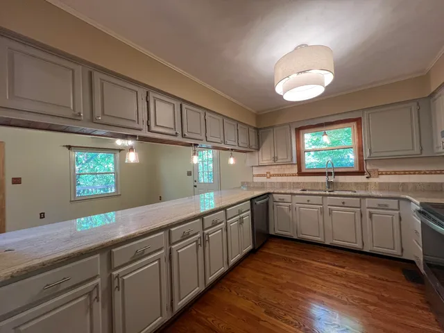 a kitchen with granite countertop cabinets stainless steel appliances a sink and a window