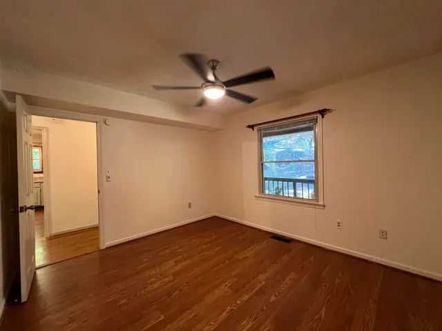 a view of an empty room with wooden floor and a window