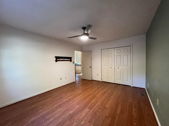 a view of empty room with wooden floor and ceiling fan