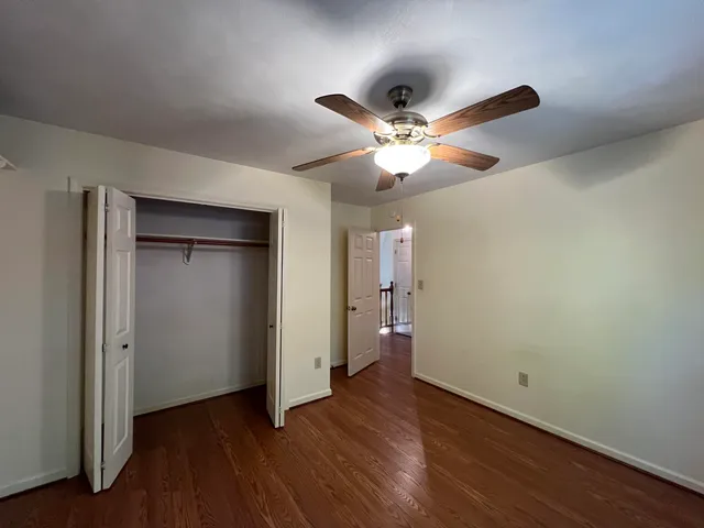 an empty room with wooden floor and a ceiling fan