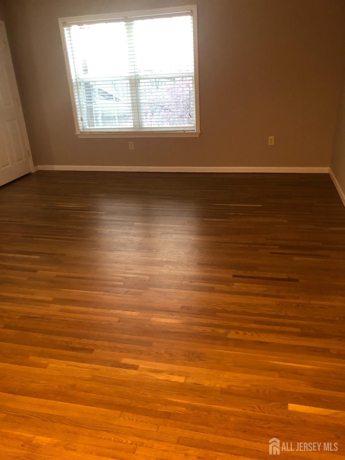 566 Cliff Road, Unit C Sewaren, NJ 07077 - Photo 4 of 14 an empty room with wooden floor and windows