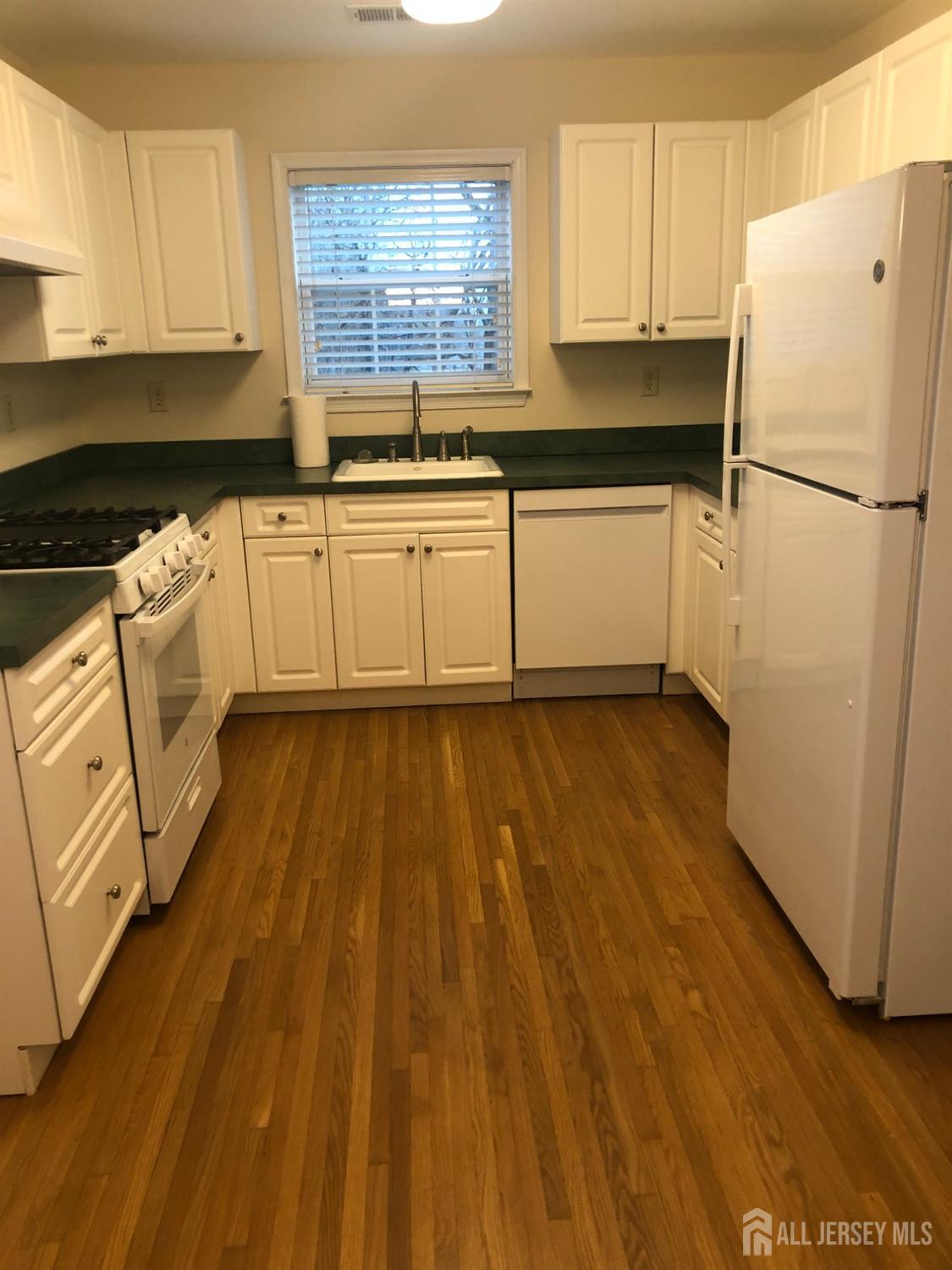 566 Cliff Road, Unit C Sewaren, NJ 07077 - Photo 5 of 14 a kitchen with wooden floors and white appliances