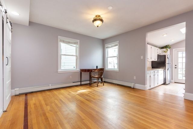 a view of an empty room with window and wooden floor