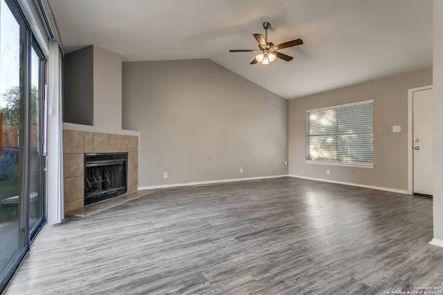 an empty room with fan fireplace and windows