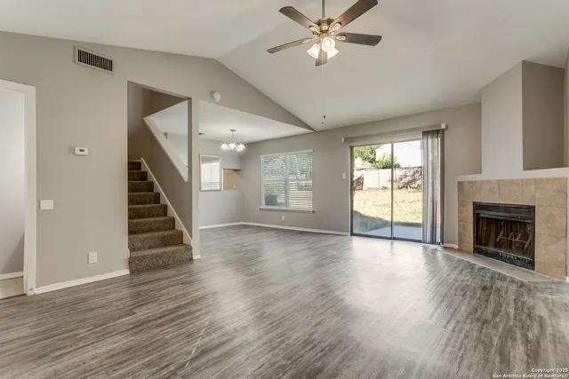 a view of an empty room with wooden floor fireplace and a window