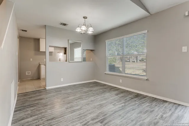 a view of an empty room with a window and wooden floor