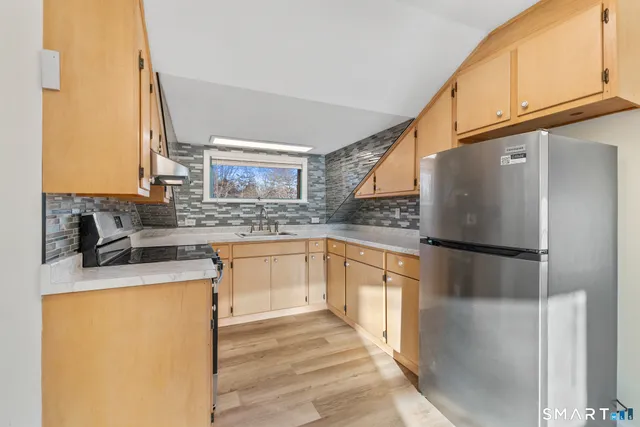 a kitchen with stainless steel appliances granite countertop a refrigerator a sink and white cabinets