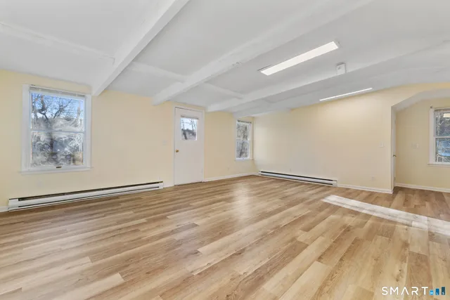 a view of an empty room with wooden floor and a window