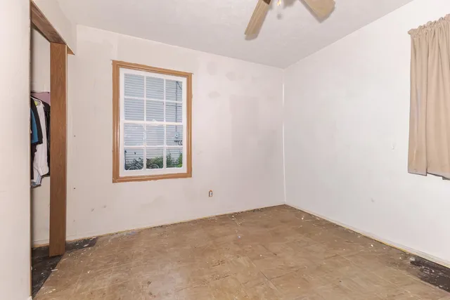 an empty room with a window and a ceiling fan