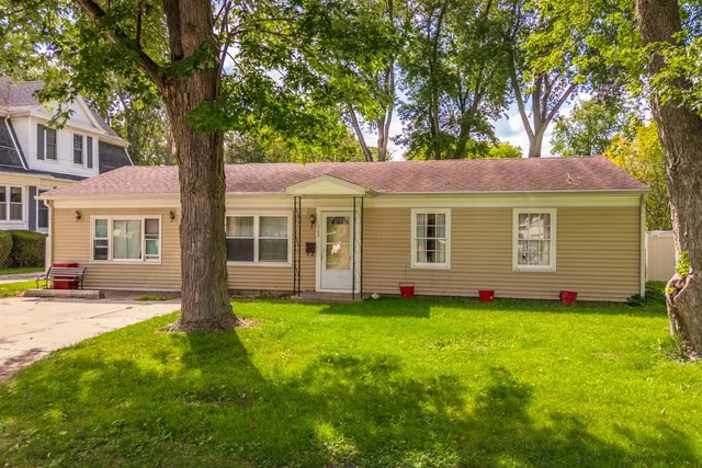 a view of a house with a yard and large tree