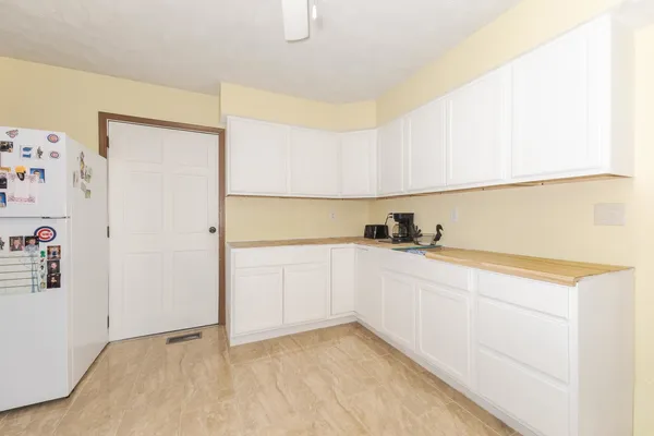 a view of a kitchen with white cabinets and a refrigerator