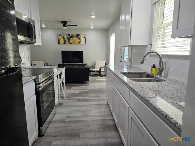 a kitchen with granite countertop a sink and a stove top oven