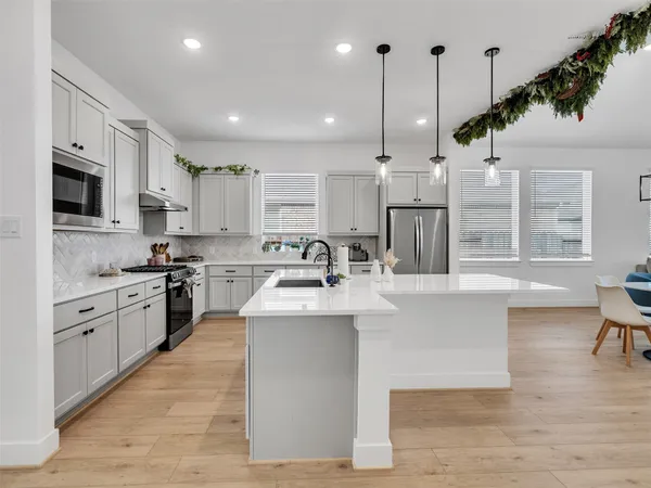 a kitchen with stainless steel appliances granite countertop a sink a stove a refrigerator cabinets and chairs