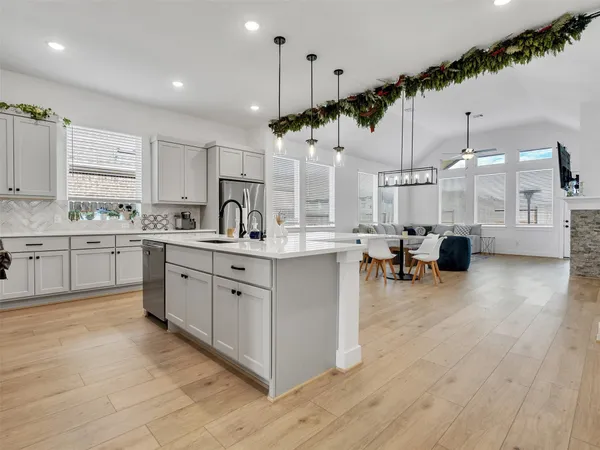 a large white kitchen with a large window and stainless steel appliances
