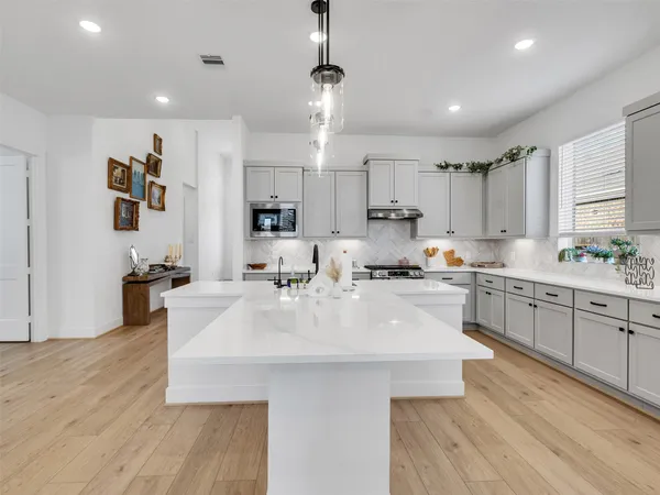 a large white kitchen with lots of counter space wooden floor and appliances