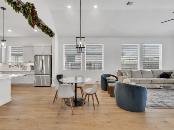 a living room with couches chairs and kitchen view with wooden floor