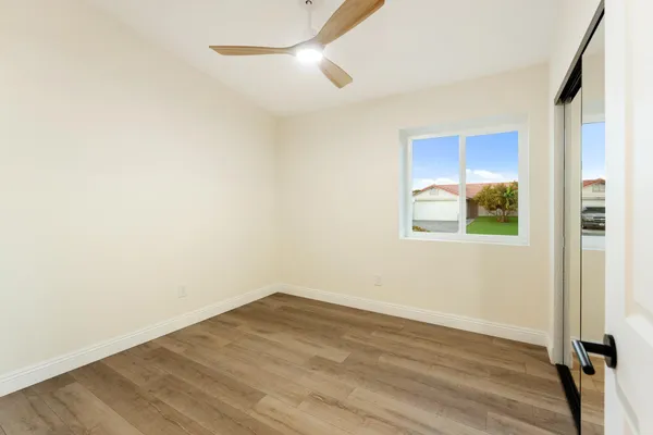 an empty room with wooden floor cabinet and windows