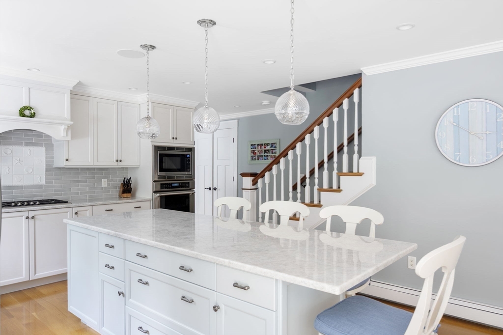 25 Mohawk Way Cohasset, MA 02025 - Photo 11 of 34 a kitchen with stainless steel appliances kitchen island granite countertop a table chairs and a refrigerator