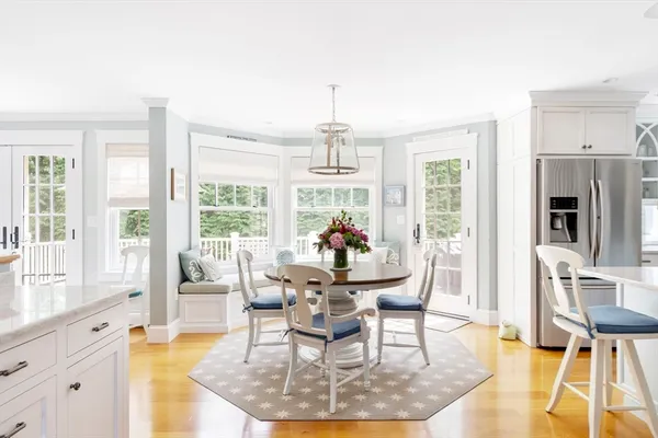 a dining room with wooden floor a chandelier a glass table and chairs