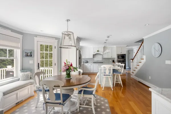 a dining room with wooden floor a chandelier a wooden table and chairs