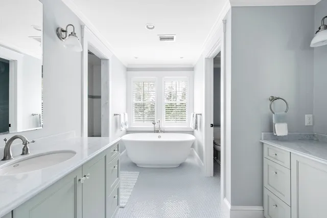 a spacious bathroom with a double vanity sink a mirror and a bathtub