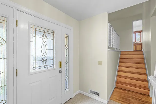 a view of a hallway with front door wooden floor and stairs