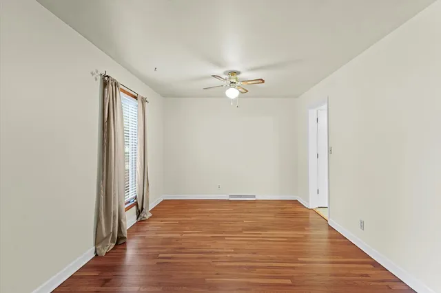 an empty room with wooden floor and fan