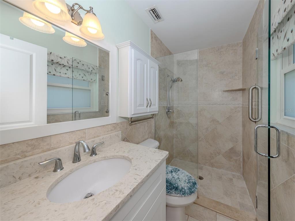 1977 Beach Road, Unit 83 Englewood, FL 34223 - Photo 18 of 48 a bathroom with a granite countertop sink a toilet and shower