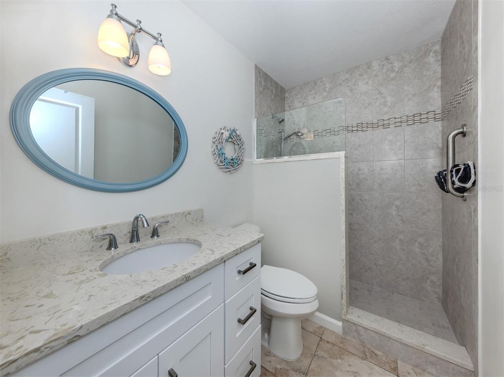 1977 Beach Road, Unit 83 Englewood, FL 34223 - Photo 20 of 48 a bathroom with a granite countertop toilet sink and mirror